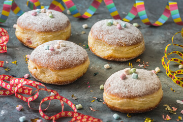 Krapfen, Berliner or donuts with streamers, confetti and mini marshmallows on gray background....