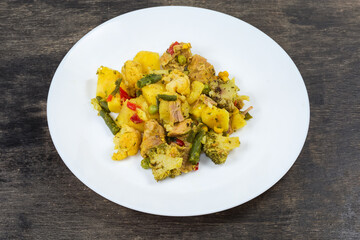 Vegetable ragout portion with meat on plate on black surface