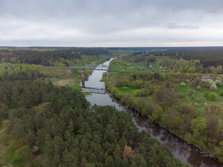 Fototapeta na wymiar River among forest and railroad bridges across it, aerial view