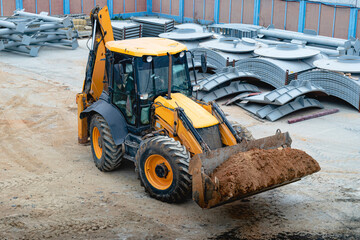 A multipurpose excavator with a front bucket transports soil to the construction site. View from above. Construction machinery for earthworks.