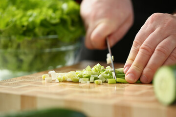 Professional chef cut spring onion with sharp knife on cutting board