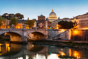 Fototapeta na wymiar View of Rome with the Victor Emmanuel II bridge across the Tiber and the dome of St. Peter's cathedral in the Vatican from the Sant'Angelo bridge at sunset, Italy