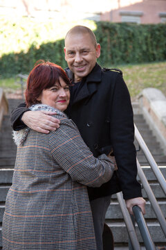 Elderly Couple Posing With Their Arms Around Each Other In The City