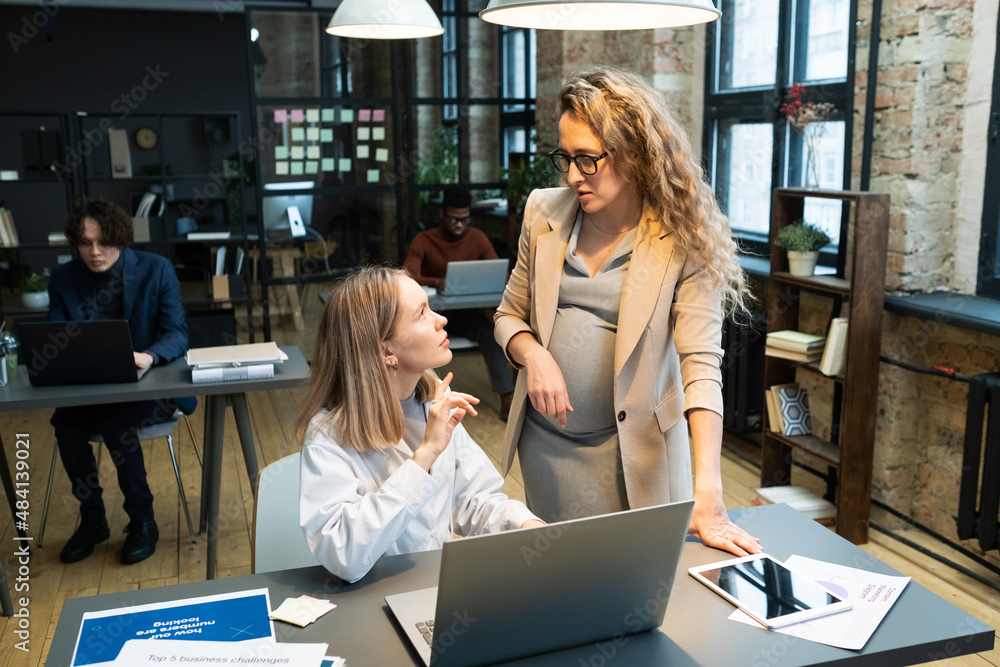 Aufkleber two young caucasian businesswoman in smart casualwear discussing working points while one of them si