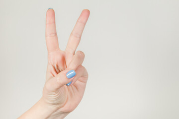 Close-up view color stock photography of one manicured female hand showing two fingers up. Woman making Victory or Peace gesture sign