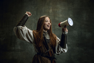 Excited young medieval warrior or knight with dirty wounded face shouting at megaphone isolated...