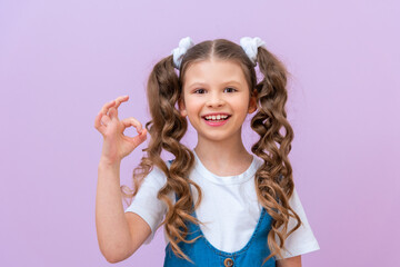 A happy young girl in a white T-shirt and a denim dress, shows the ok sign and smiles, Everything is fine,