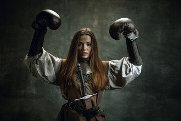 Portrait of brave girl, medieval warrior or knight with dirty wounded face in boxing gloves...