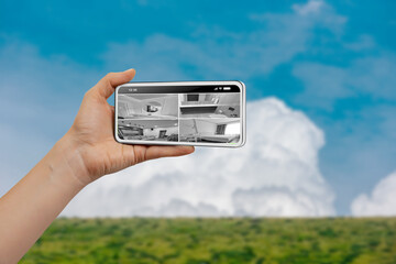 Female hand holding smartphone and monitoring video footage against blue sky mountain background