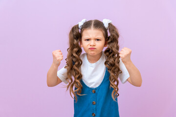 A disgruntled and angry child on an isolated background. Baby gets angry and shows his fists.