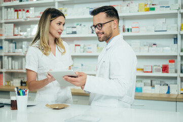 Obraz premium Happy young male and female colleagues pharmacist working in a pharmacy