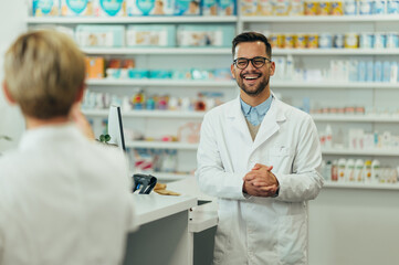 Happy young male pharmacist working with senior colleague in a pharmacy