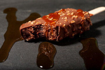 Haagen-Dazs chocolate ice cream with almonds. On a stick. On a black granite background
