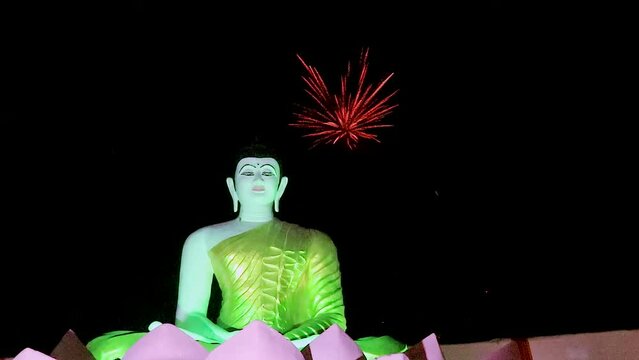 white buddha statue with crackers sparkle in black background at night from flat angle