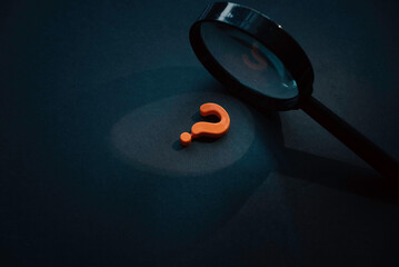 Questions and answers concept. Question symbol and magnifying glass on dark background.