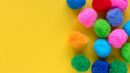 Colorful cotton balls on yellow background with copy space.