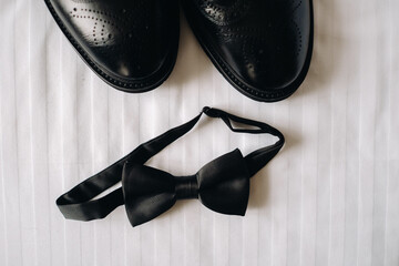 Classic black bow tie and black boots on the surface