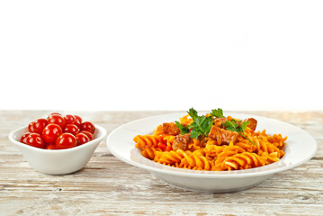 Pasta with meat and tomatoes in a white plate. Pasta on a shabby wooden table. Copy space and free space for text near food.
