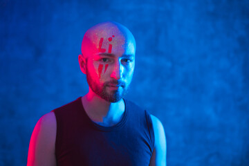 Portrait of calm young bald man with glowing body art. Beautiful fantastic drawing on skin, copy space.