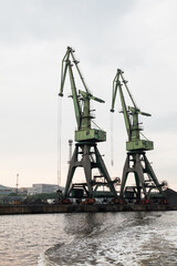 Green port cranes, close-up vertical photo