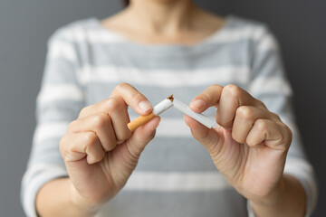 Portrait young woman holding broken cigarette in hands. Happy female quitting refusing smoking...