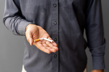 Portrait young man holding broken cigarette in hands. Happy male quitting refusing smoking...