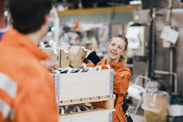 Smiling female worker talking with male coworker while working in warehouse