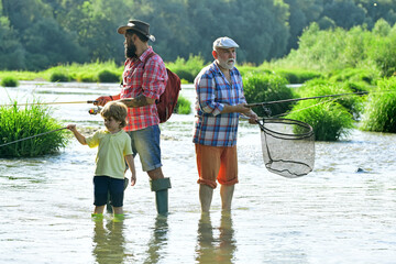 Dad and son fishing at lake. Grandfather, father and grandson fishing together. Grandson with...