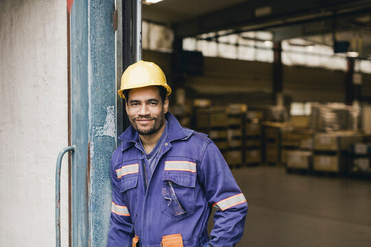 Portrait of smiling blue-collar worker wearing hardhat in warehouse
