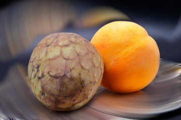 creative still life of a peach and a custard apple