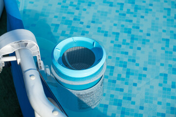 Skimmer on a round frame pool of a country house. Blue skimmer to clean pool in clear water. Side...