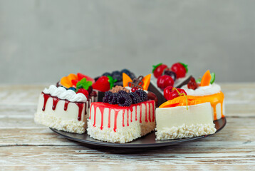 Set of different cakes on a white background. Pieces of cakes with chocolate and fruit icing. Sweets on a shabby wooden table.