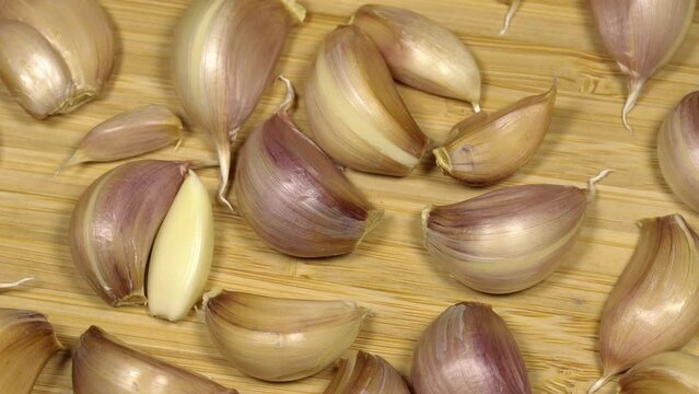 Fresh garlic cloves on a wooden table, rotation background. Loop motion