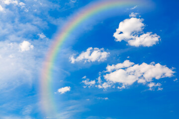 Rainbow at summer sky . Rainbow with white clouds at blue sky 