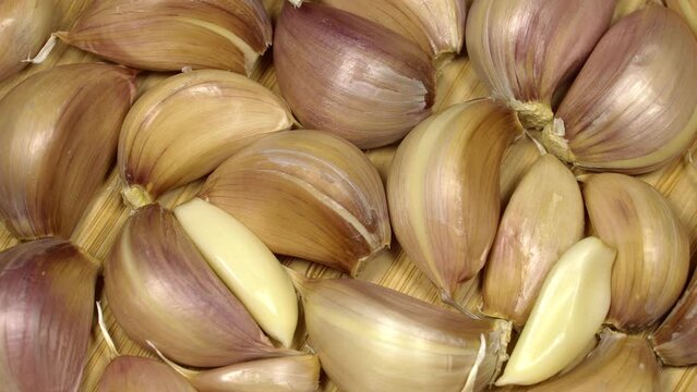 Fresh garlic cloves on a wooden table, rotation background. Loop motion