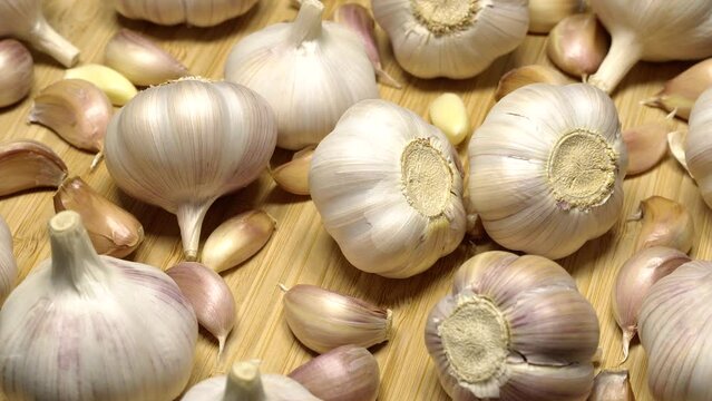 Fresh garlic bulbs and cloves on a wooden table, rotation background. Loop motion