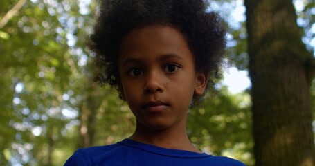 Portrait of a young African American child walking alone in the park. Kid walking without adult...