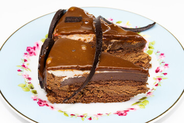 A slice of chocolate, cream and caramel cake on flower plate