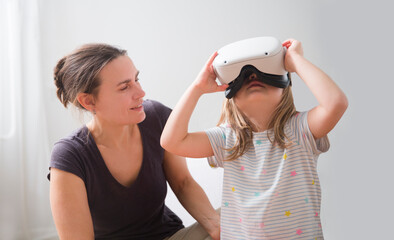 virtual reality. loving family spends time together. mom and Cute little child girl playing game in virtual reality glasses.
