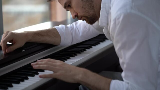 The composer-pianist in a white shirt enthusiastically improvises, composes music and plays the piano with one left hand.