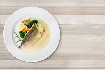 Plate of fried fish fillet with vegetables on the desk