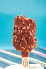 
Chocolate ice cream with almonds. On a stick. On a blue background
