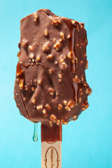 
Chocolate ice cream with almonds. On a stick. On a blue background