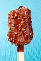 
Chocolate ice cream with almonds. On a stick. On a blue background