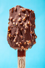 
Chocolate ice cream with almonds. On a stick. On a blue background