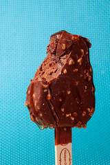 
Chocolate ice cream with almonds. On a stick. On a blue background