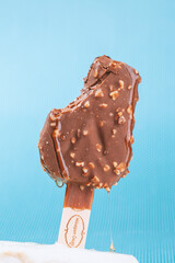 
Chocolate ice cream with almonds. On a stick. On a blue background