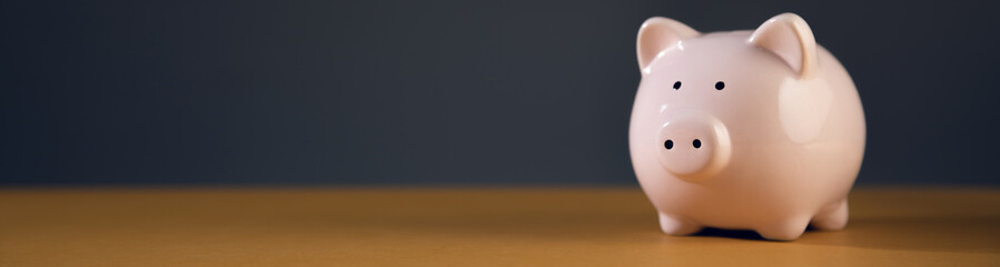 Pink piggy bank on wooden table.