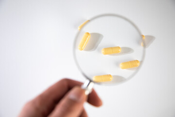 Hand holding magnifying glass with pills