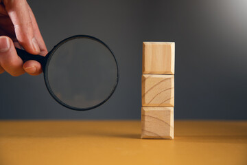 man holding magnifying glass with wooden cubes